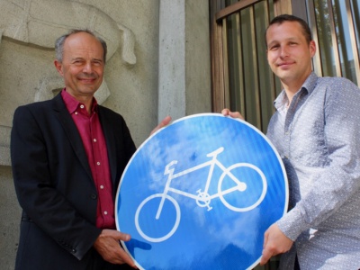 Silas Hobi übergibt Stadtrat Richard Wolff symbolisch ein Schild zur Förderung des Velos